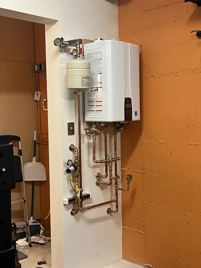 Plumbing technician inspecting water heater connections in Hamilton